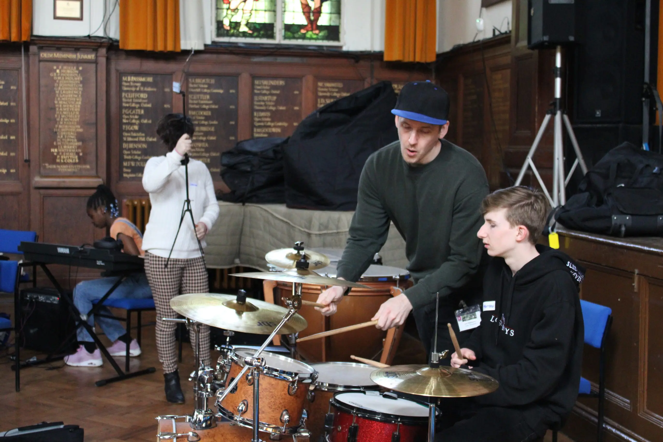Teacher demonstrating to student on the drums in the percussion section of an Orchestra One Course