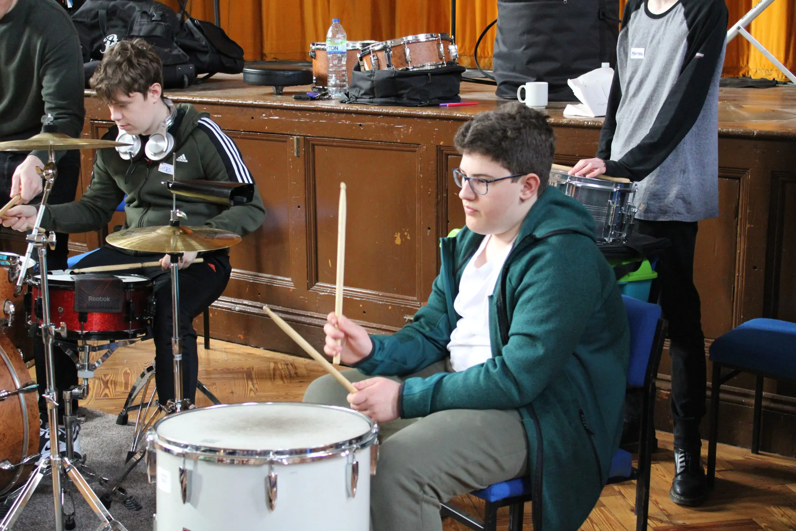 Young male students playing the drums and percussion at an Orchestra One course.