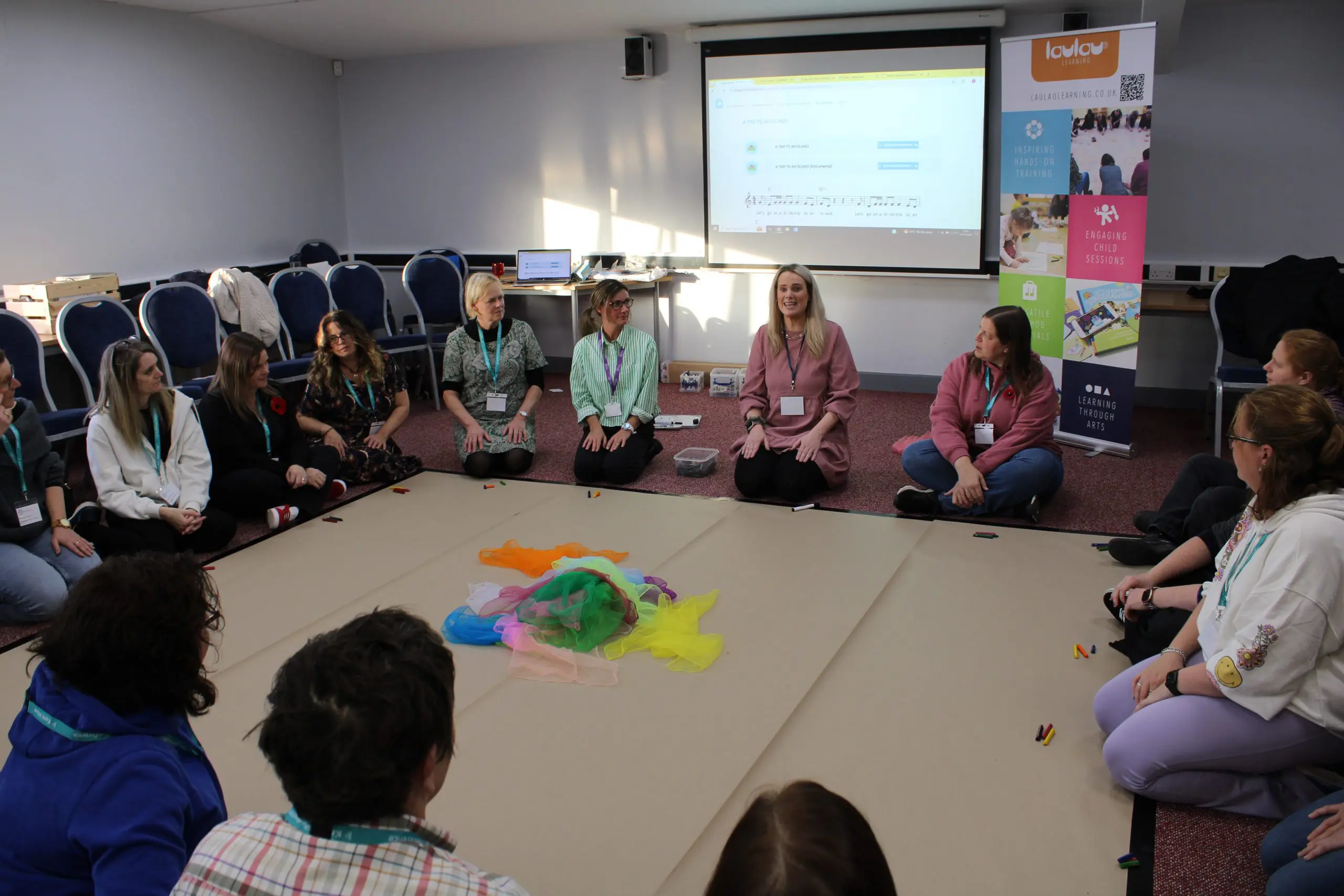Teachers and staff sat in a circle on the floor in a workshop at the Kent and Medway Music Conference