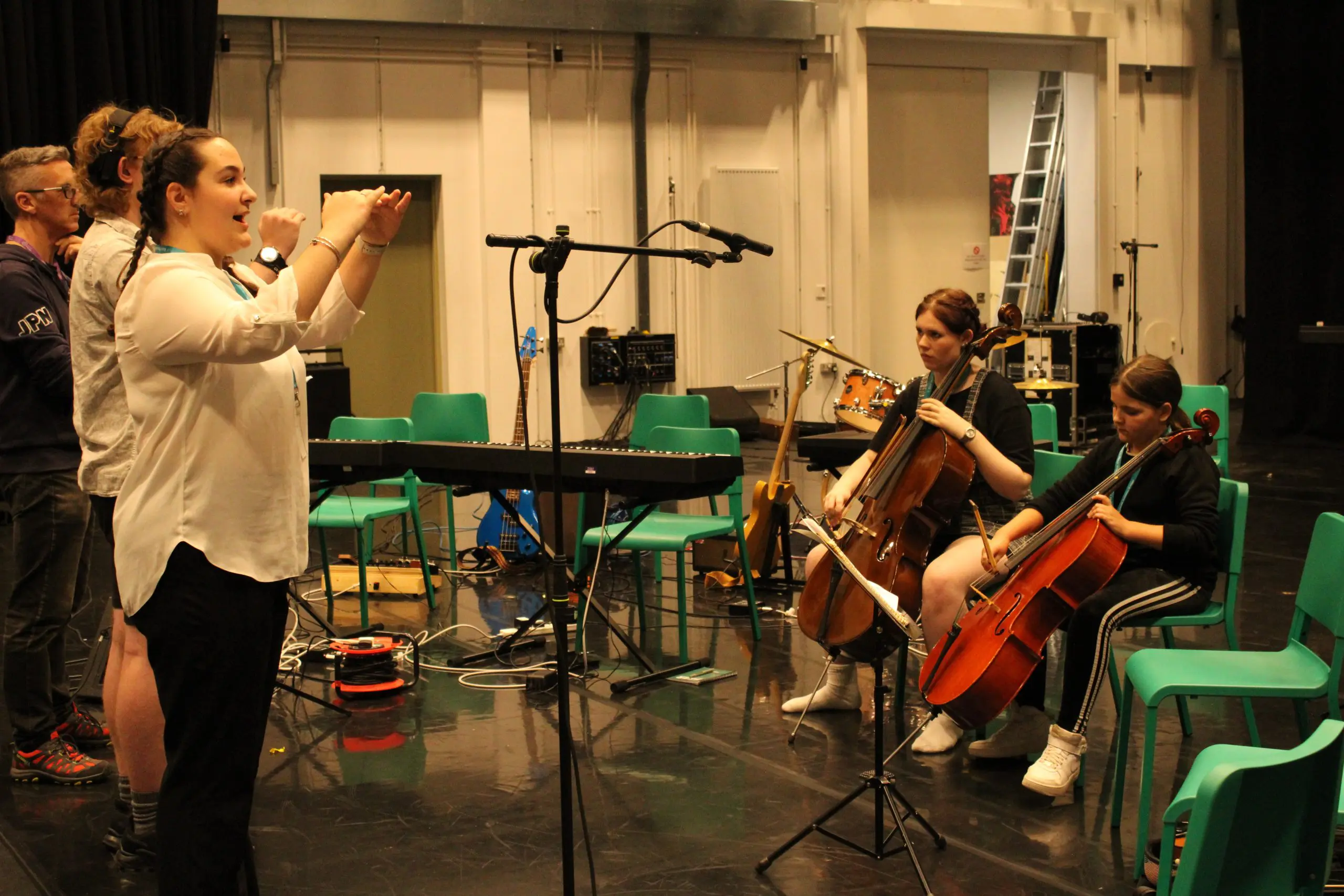 Young students collaborating making music singing and playing the cello.